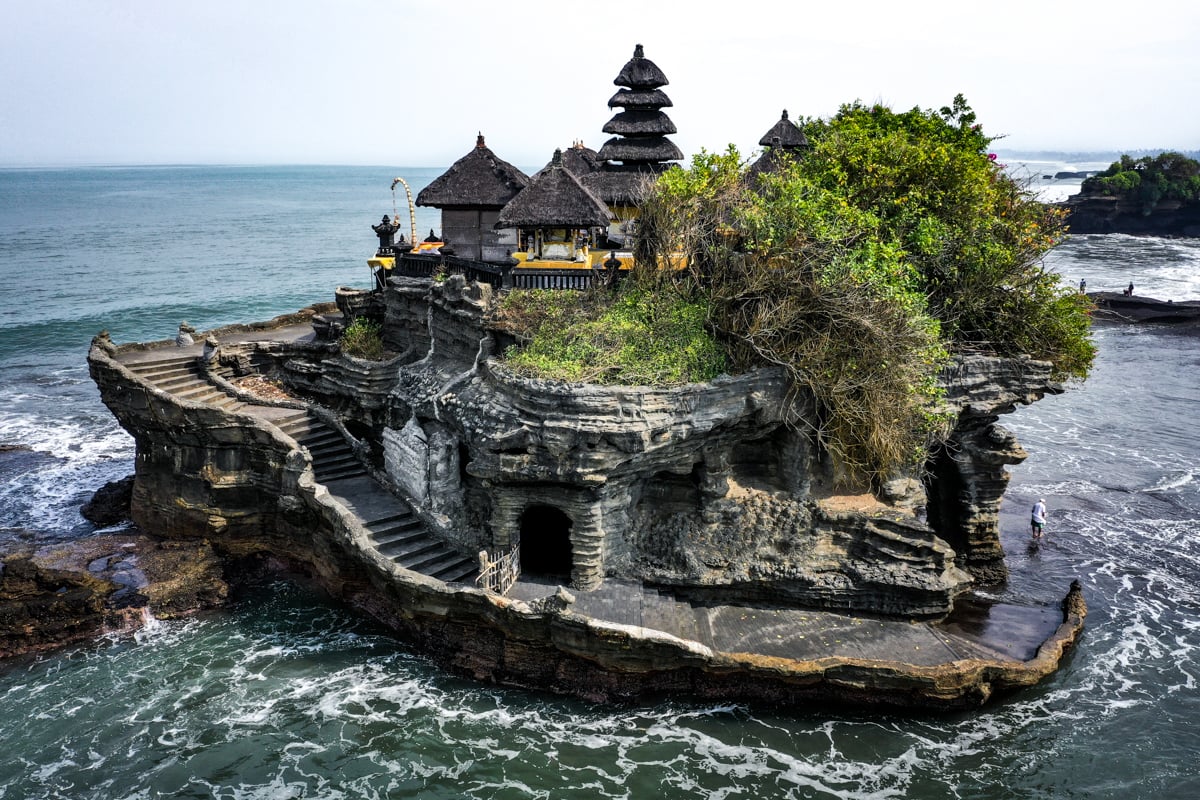 Pura Tanah Lot yang megah berdiri di atas batu karang, dikelilingi oleh ombak laut Bali